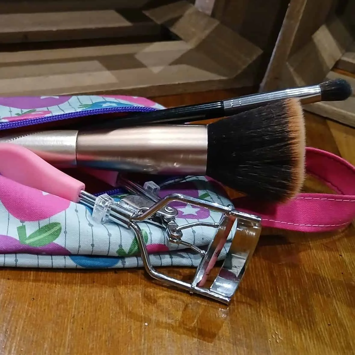 Trousse en tissu imprimé colorée, posée sur une table avec des produits de beauté, pratique et girly