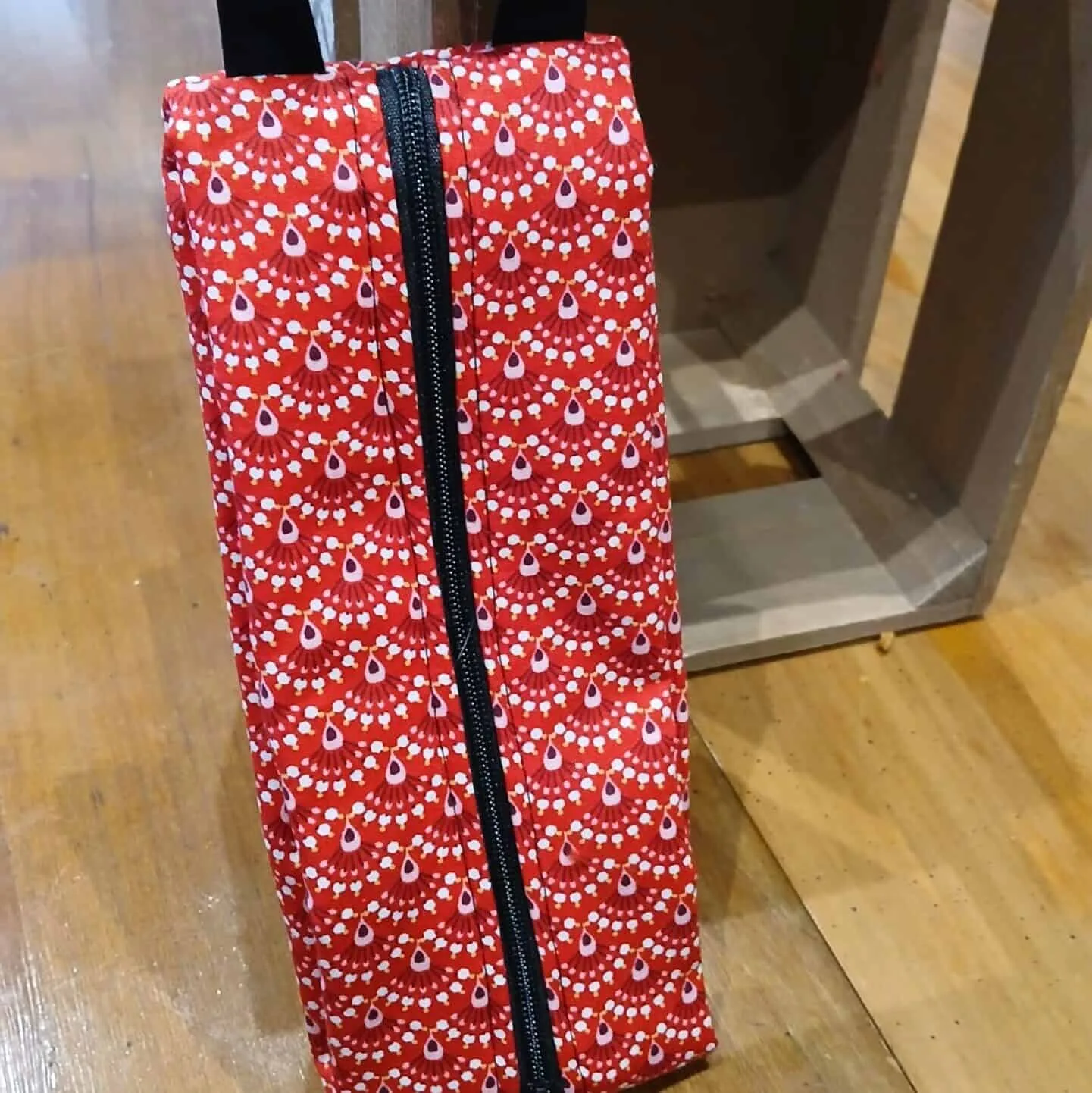 Trousse en tissu imprimé rouge avec motifs floraux, fermeture éclair noire et anse pratique