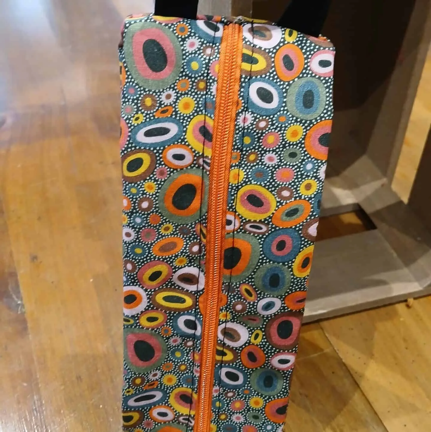 Trousse en tissu avec motifs de cercles colorés, fermeture éclair orange et anse pratique